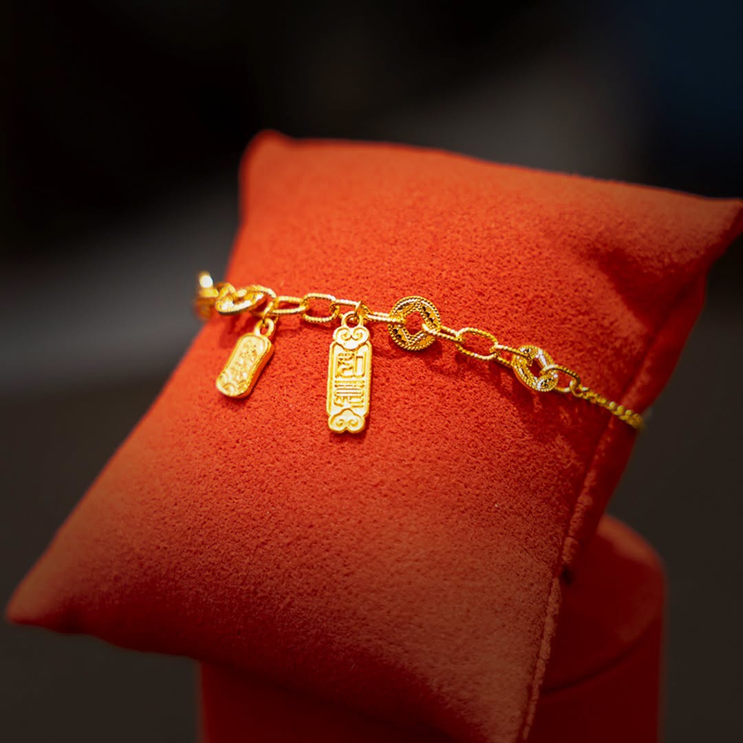 Gold charm bracelet with Fu character and coin-style pendants